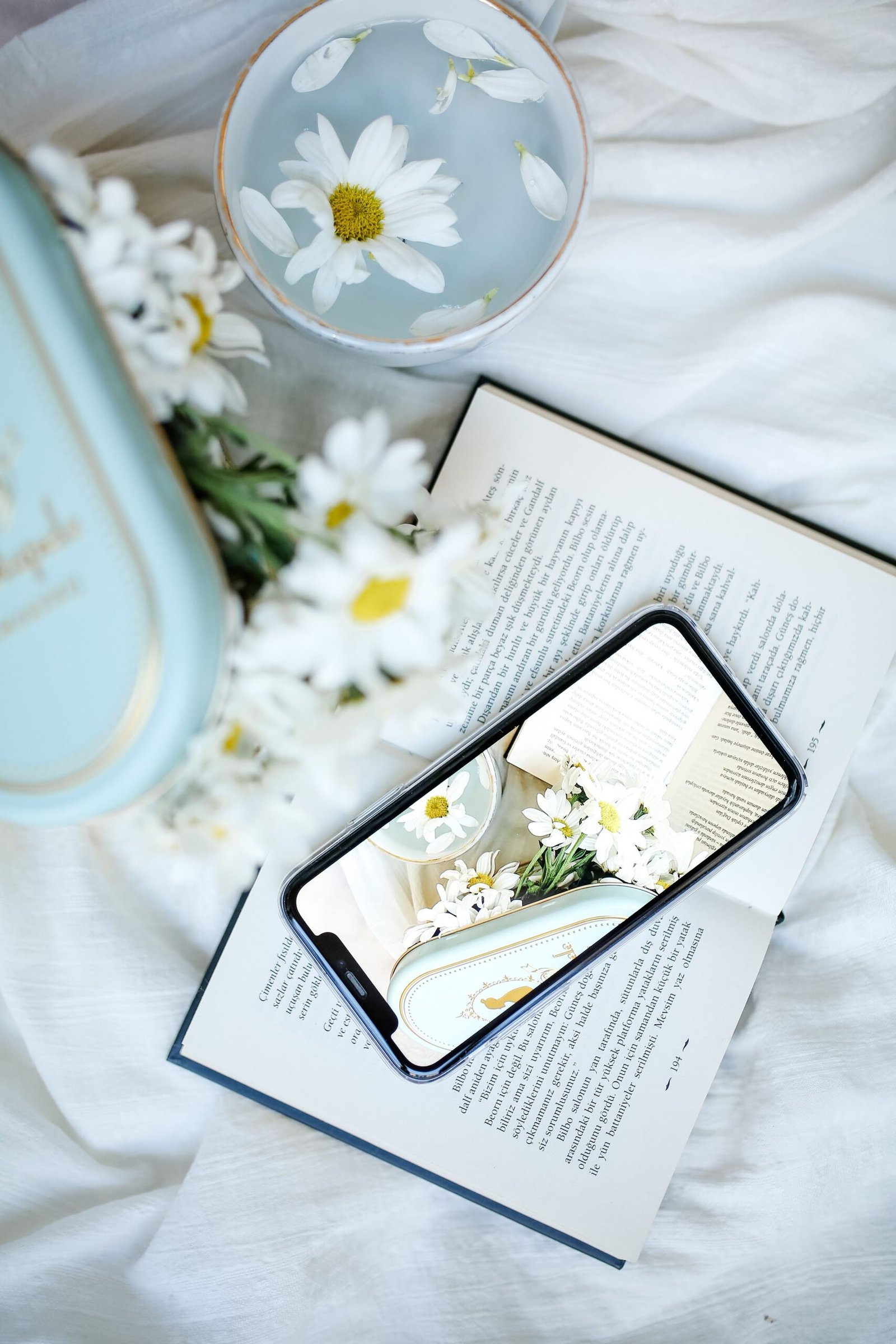 Phone displaying book content beside an open book and flowers