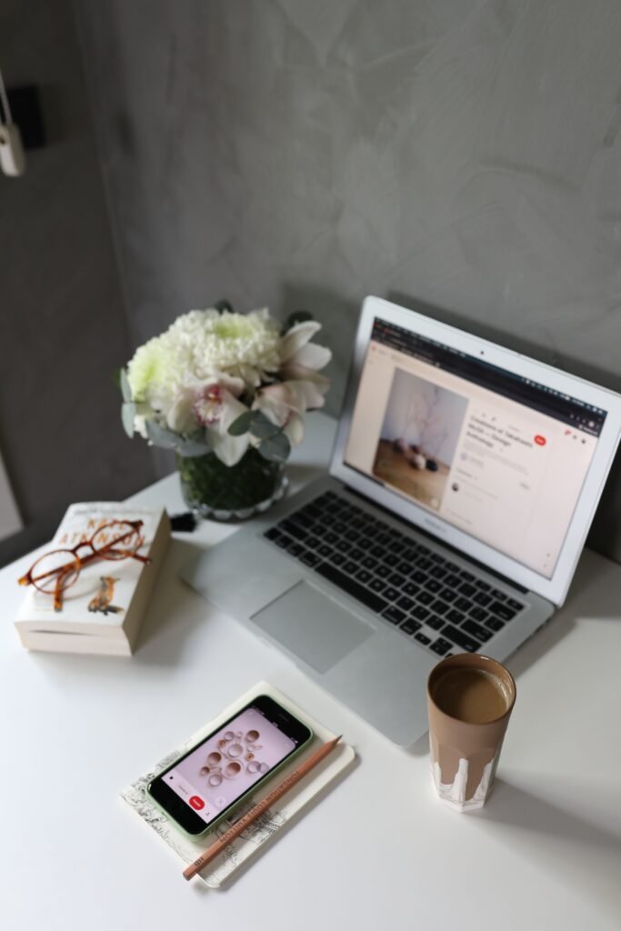 Author social media management workspace with laptop, smartphone, books, and coffee
